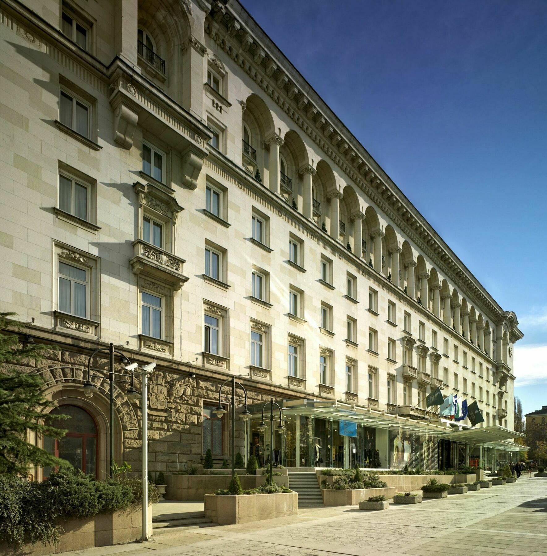 Sofia Balkan Palace Hotel Exterior photo The photo shows a large building that appears to be a hotel or an administrative structure. The architecture features a classic style with multiple windows, balconies, and decorative elements such as ornate moldings. The facade is primarily made of l